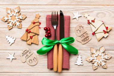 Çatal ve bıçağın üst görüntüsü ahşap arka planda peçeteyle bağlanmış. Noel süsleri ve yılbaşı ağacı. Tasarımınız için boş alanı olan mutlu tatil kavramları.