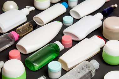 Renkli arka plandaki kozmetik ürünleri için farklı boyutlarda şişeler ve kavanozlar. Fotokopi alanı ile yüz ve vücut bakımı kavramı.