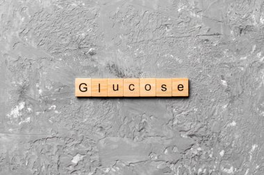 Tahta bloğa yazılmış GLUCOSE kelimesi. Çimento masasındaki GLUCOSE metni desing, konsept için.