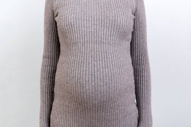 Gri arka planda gri elbiseli hamile karnı kesilmiş. Kadın bebek bekliyor. Boşluğu kopyala.