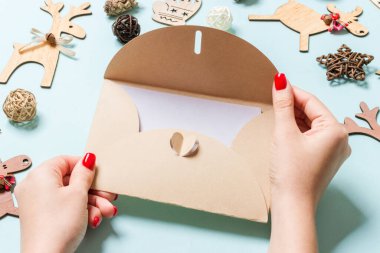 Bayram süslemelerinden yapılmış mavi arka planda bir zarf tutan kadının üst görüntüsü. Noel zamanı konsepti.