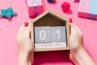Pembe arka planda kadınların el ele tutuşmalarının en üst görüntüsü. 1 Ocak 'ta. Tatil süslemeleri. Yeni yıl konsepti.