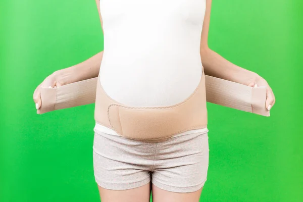 Zbliżenie Kobiety Ciąży Ubieranie Elastyczne Macierzyństwo Zielonym Tle Miejsca Kopiowania — Zdjęcie stockowe