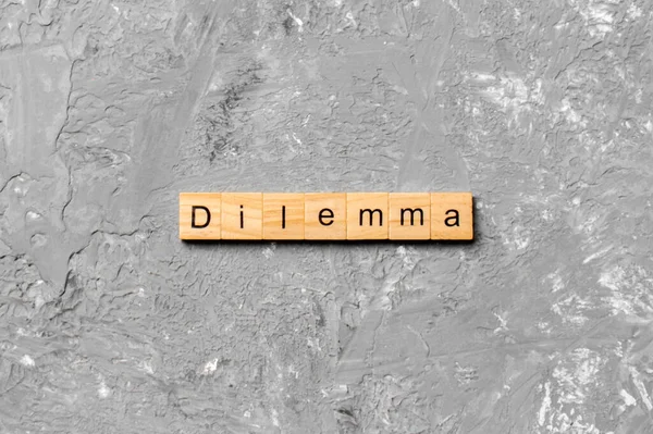 Tahta blokta yazan ikilem kelimesi. Desing, konsept için çimento masanın üzerindeki ikilem metni.