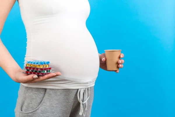 围观孕妇拿着纸杯和一堆水泡药丸 背景五彩斑斓 有复制空间 治疗概念 — 图库照片