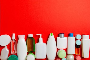 Farklı kavanozlardaki kozmetik ürünlerinin ve renkli arka plandaki şişelerin üst görüntüsü. Kopyalama alanı olan konteynırların kapatılması.