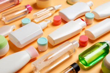 Renkli arka plandaki kozmetik ürünleri için farklı boyutlarda şişeler ve kavanozlar. Fotokopi alanı ile yüz ve vücut bakımı kavramı.