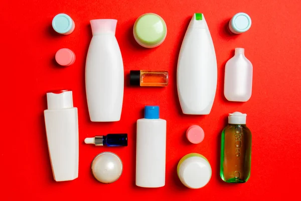 Top view of different cosmetic bottles and container for cosmetics on colored background. Flat lay composition with copy space.