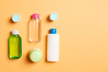 Kozmetik SPA marka modeli, fotokopi alanı olan üst görünüm. Renkli arka planda duran krema tüpleri ve kavanozları..