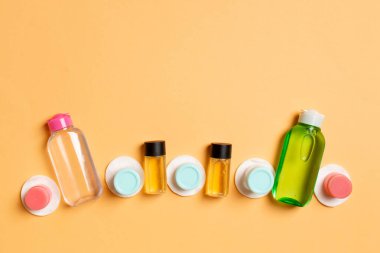 Renkli arka planda seyahat etmek için bir grup küçük şişe. Fikirlerin için uzayı kopyala. Kozmetik ürünlerin düz bileşimi. Pamuklu krema kaplarının üst görüntüsü.