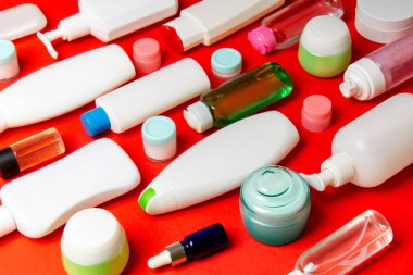 Renkli arka plandaki kozmetik ürünleri için farklı boyutlarda şişeler ve kavanozlar. Fotokopi alanı ile yüz ve vücut bakımı kavramı.