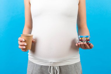 Elinde kağıt bardakla hamile bir kadının renkli arka planda fotokopi çekilen haplarla su toplamasına yakın. Tedavi kavramı.