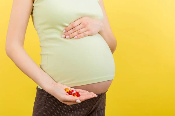 妊娠中の女性の手の中の丸薬のヒープの閉じますコピースペースとカラフルな背景で ヘルスケアの概念 — ストック写真