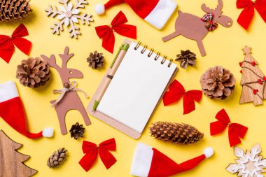 Noel oyuncakları ve dekorasyonlarla dolu sarı bir arka plan. Defterin en üst görüntüsü. Mutlu yıllar konsepti.