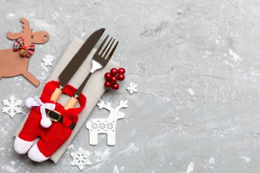 Noel süslemeleri ve çimento arka planında ren geyiği olan peçetedeki yeni yıl aletlerinin en üst görüntüsü. Fotokopi alanı ile Noel yemeği konsepti.