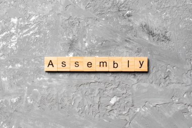 Tahta bloğa yazılmış bir kelime. Çimento sehpasında senin desing, konsept için ASSEMBLY metin.