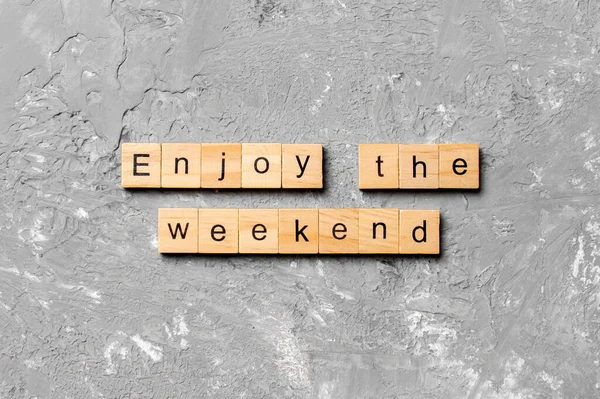 Enjoy the weekend word written on wood block. Enjoy the weekend text on cement table for your desing, Top view concept.
