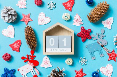 Yeni yıl oyuncakları ve mavi arka planda süslemelerle çevrili ahşap takvimin üst görüntüsü. 1 Ocak 'ta. Noel zamanı konsepti.