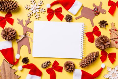 Noel oyuncakları ve dekorasyonlarla dolu sarı bir arka plan. Defterin en üst görüntüsü. Mutlu yıllar konsepti.