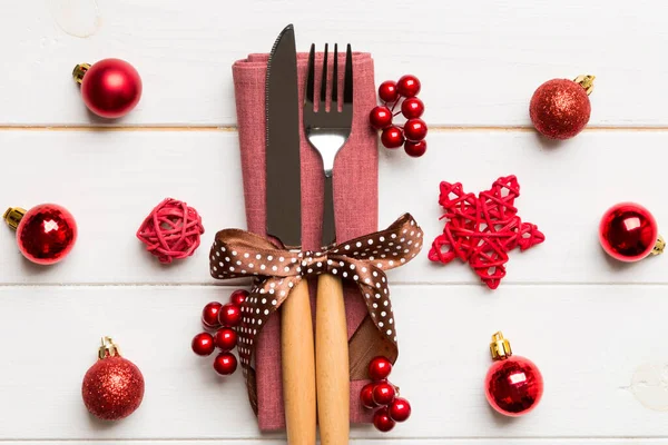 Tahta arka planda çatal ve bıçak seti. Noel süslemeleri ve fotokopi alanı olan oyuncaklar. Yeni yıl arifesi kavramı.