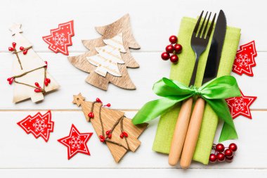Çatal ve bıçağın üst görüntüsü ahşap arka planda peçeteyle bağlanmış. Noel süslerini ve yeni yıl ağacını kapatın. İyi bayramlar..