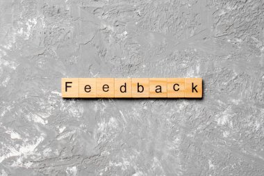 Tahta blokta yazan geri bildirim kelimesi. Deksing, konsept için çimento masadaki geri bildirim metni.