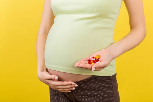 妊娠中の女性の閉じ込めコピースペースとカラフルな背景で彼女の手の中にビタミン薬のスタックを保持します 医学の概念 — ストック写真