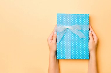 El ele tutuşmuş, hediye paketlenmiş ve altın kaplama arka planda fotokopi alanı ile süslenmiş bir kadın. Noel ve tatil konsepti.
