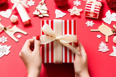 Noel hediyesini kırmızı arka planda tutan kadınların üst görüntüsü. Tatil süslemeleri. Yeni yıl tatili konsepti.