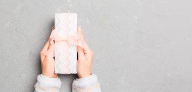 Üst görüşlü kadın ellerinde gri çimento ahşap zemin üzerinde renkli yay ve fotokopi alanı olan bir kutu tutuyor..