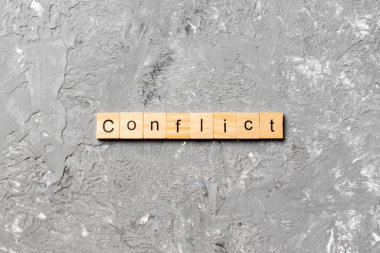 Tahta bloğa yazılmış KONFLICT kelimesi. Deksing, konsept için çimento masadaki CONFLICT metin.