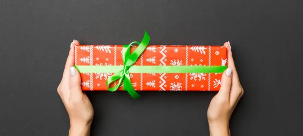 手のひらにクリスマスや他の休日手作りプレゼントボックスパッケージを保持する女性の手のトップビュー コピースペースと黒の背景にフラットレイアウト — ストック写真