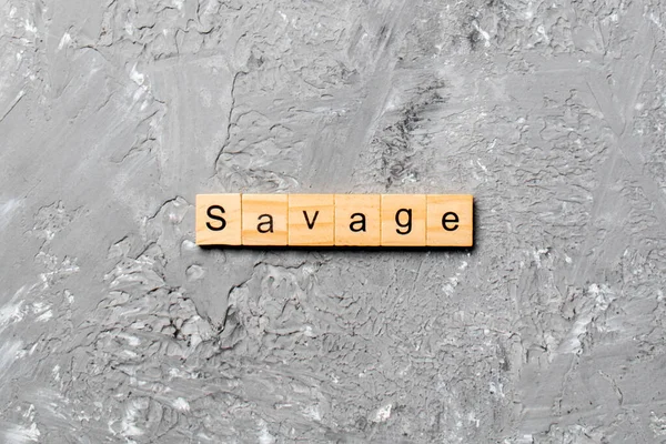 Tahta bloğa yazılmış SAVAGE kelimesi. Çimento masasındaki SAVAGE metni desing, konsept için.