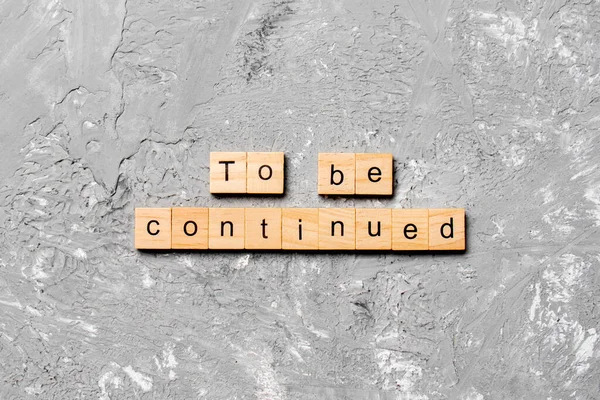 To be continued word written on wood block. To be continued text on cement table for your desing, concept.