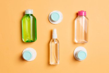 Renkli arka planda seyahat boyutunda kozmetik şişeler. Krema kavanozları düzdü. Vücut bakım stili kavramının en üst görünümü.