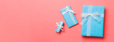 Yaşayan mercan arka planında beyaz kurdeleli kağıtlara sarılmış Noel veya diğer tatil hediyeleri. Hediye kutusu, hediye dekorasyonu renkli masa, üst görünüm.