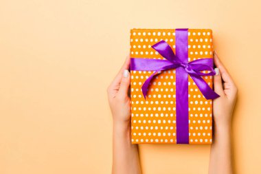 El ele tutuşmuş, hediye paketlenmiş ve altın kaplama arka planda fotokopi alanı ile süslenmiş bir kadın. Noel ve tatil konsepti.