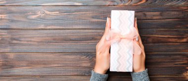 Kız Eller, Noel veya diğer bayramlarda hediye olarak siyah ahşap arka planda, fotokopi makaralı üst görünümü olan el işi kağıt hediye kutusu tutuyor..