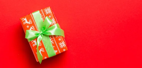 赤い背景のクリスマスや新年の日のための緑の弓とギフトボックス コピースペース付きのトップビュー — ストック写真