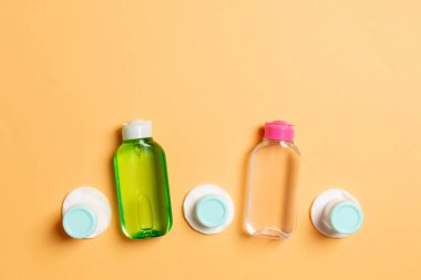 Yüz bakımı için en iyi bakış açısı: şişeler ve kavanozlar dolusu tonik, su, krem, renkli arka planda pamuk pedleri. Fikirleriniz için boş midye içeren vücut bakım konsepti.