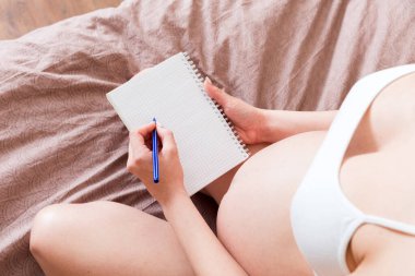 Hamile kadın not defterine not alır. Hamilelik kavramı Anne bebek bekliyor.