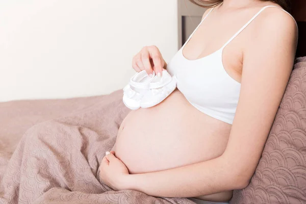 Femme Enceinte Avec Petites Chaussures Bébé Assis Sur Lit Maison — Photo