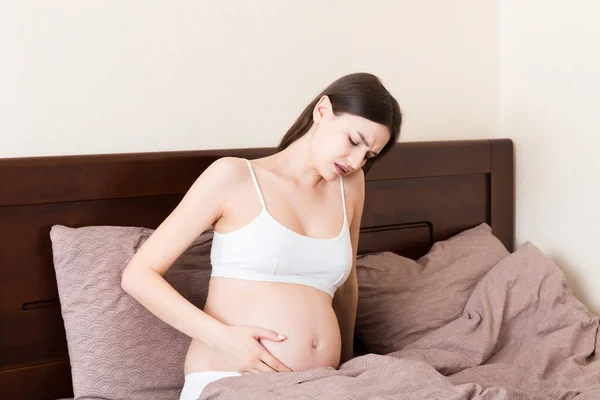 Joven Mujer Embarazada Bonita Con Dolor Sentada Cama Dormitorio Preparándose —  Fotos de Stock