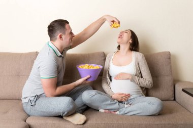 Mutlu koca, hamile karısını evdeki kanepede gevşeyen cipslerle besliyor. Müstakbel baba, anneyi bekliyor..