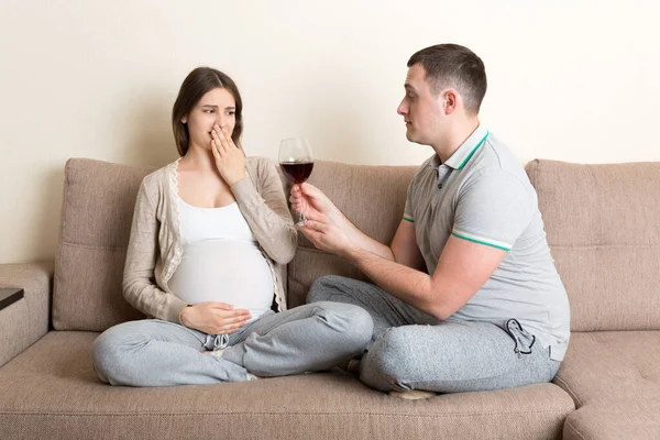 夫は妊娠中の妻に赤ワインのグラスを提供しますが 彼女は病気を感じているので 彼女は拒否し ジェスチャーを停止します 妊娠中の気分が悪い — ストック写真