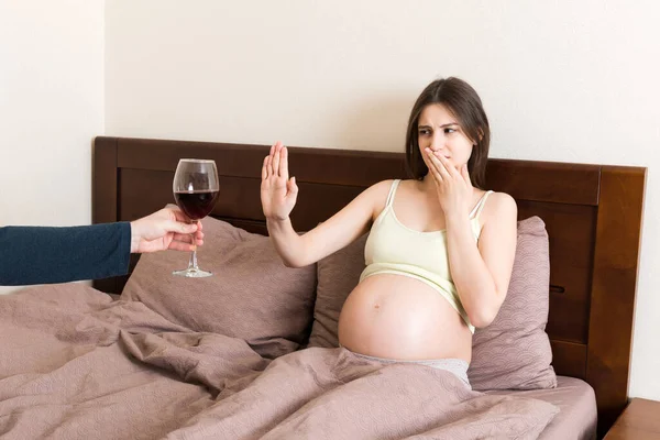 침대에 임신부는 와인을 마시기를 거부하고 술잔에 제스처를 멈춘다 임신중에는 마시지 — 스톡 사진