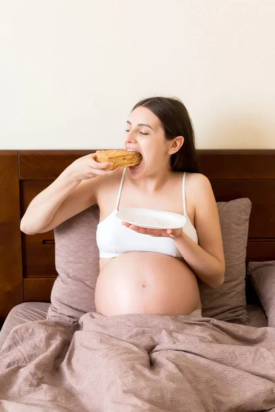 Mujer Embarazada Emocionada Está Comiendo Una Rebanada Pastel Descansando Cama —  Fotos de Stock