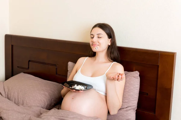 Heyecanlı Yatakta Dinlenen Hamile Bir Kadın Açgözlülükle Pasta Yiyor Ağzı — Stok fotoğraf