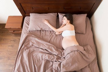 Güzel, genç, hamile bir kadın yatakta yatıyor, manzarası çok güzel. Kız, kocasının onu terk etmesinden dolayı acı çekiyor..