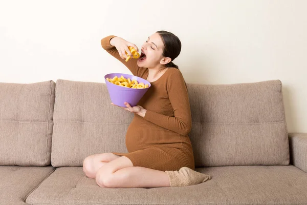Ciężarna Kobieta Siedząca Kanapie Lubi Jeść Chipsy Miski Domu Uczucie — Zdjęcie stockowe